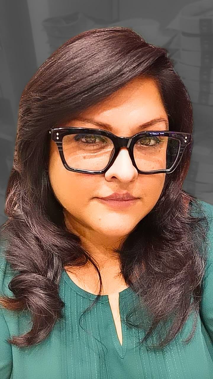 A soft-lit portrait of Mel, thoughtful and serene, in a green top and glasses—face behind MelCurates, where faith and creativity meet.