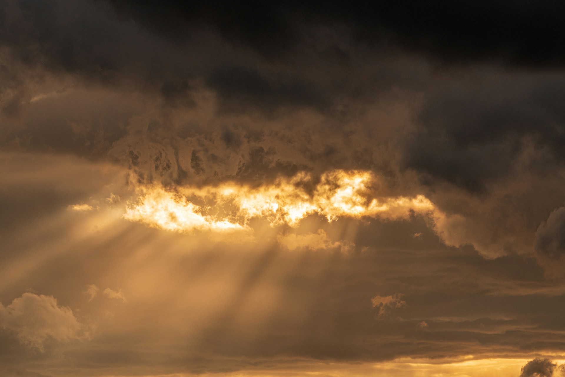 I Speak Jesus | Golden light breaking through dark stormy clouds.