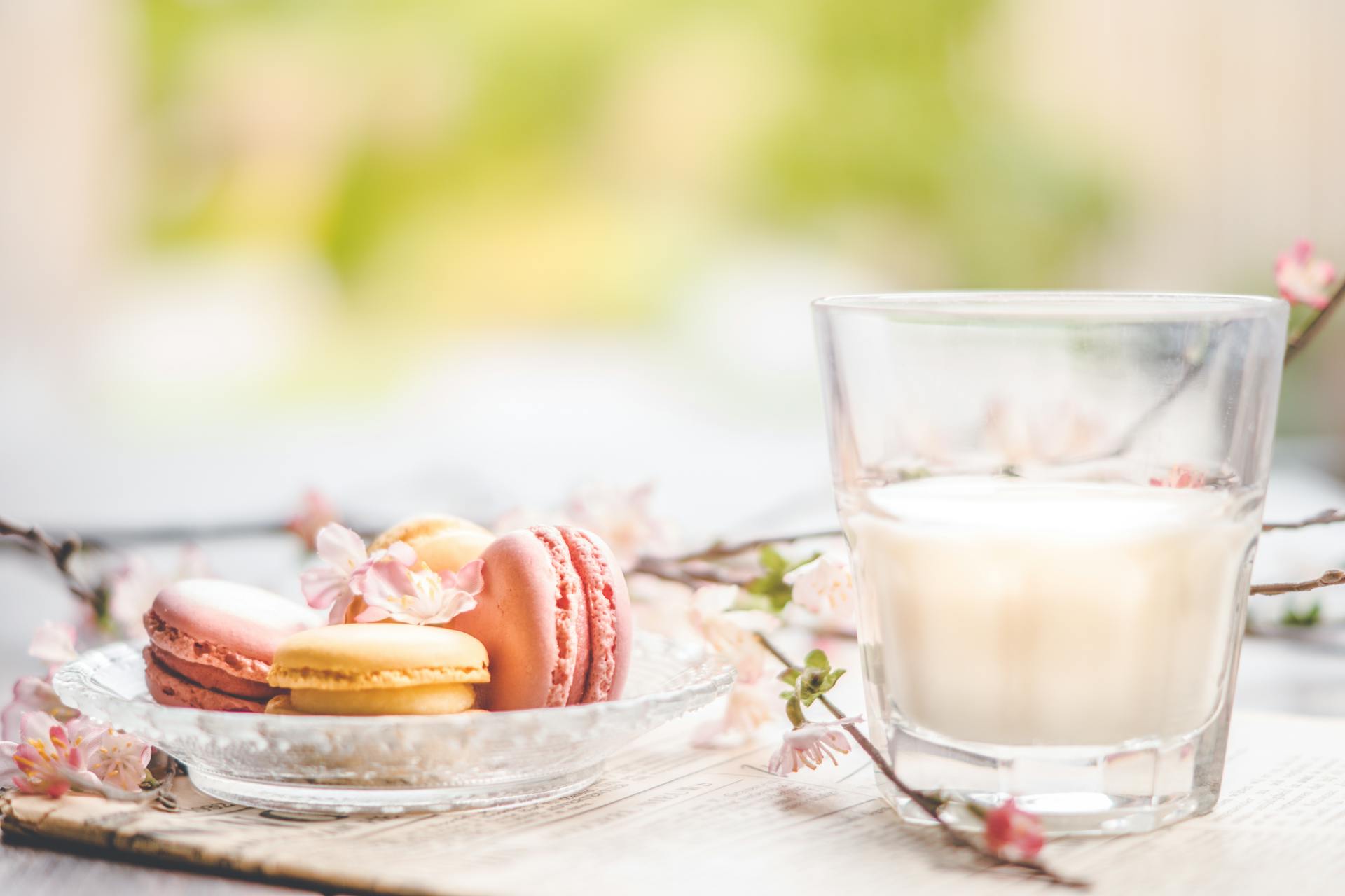 A cozy Galentine’s Day scene with pastel flowers, macarons, and a glass of milk representing Godly friendship