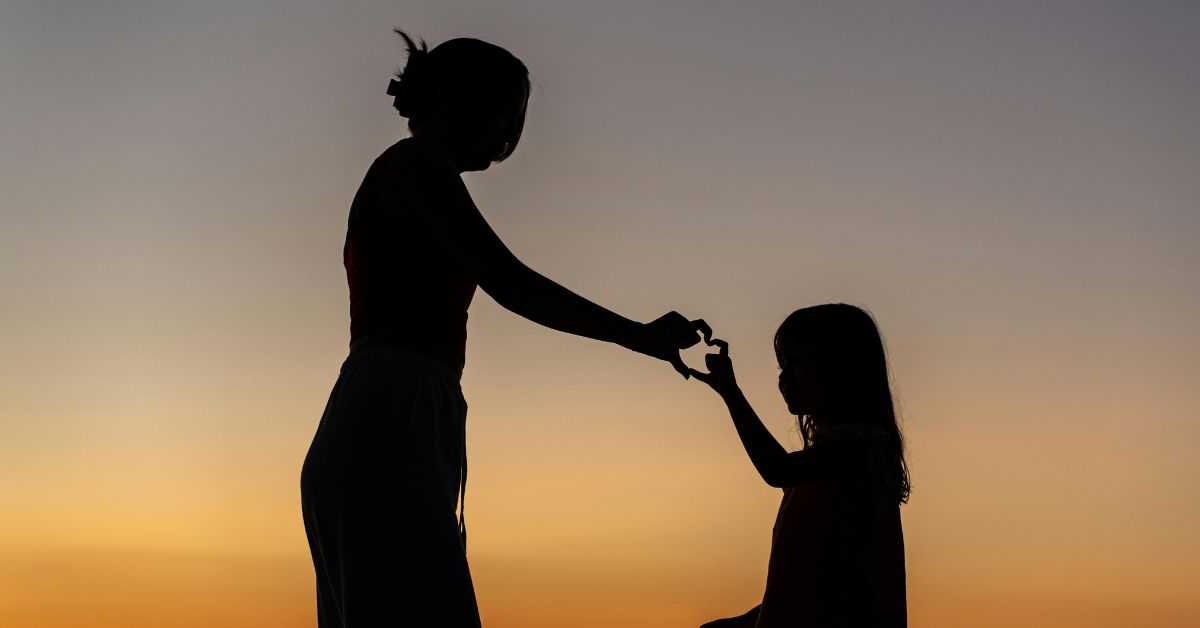 A mother's faith depicted in a mother and daughter silhouette at sunset representing Christian motherhood, and the loving spiritual legacy passed from one generation to the next.